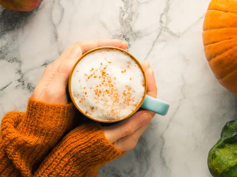 Close-up of hands holding a cup with a drink made from pumpkin