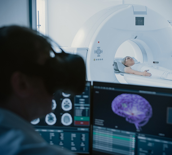 A physician in a medical room wearing a virtual reality headset to monitor a patient undergoing a scan
