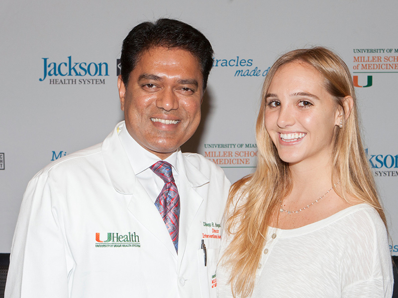 Isabel Vinueza standing next to doctor Yavagal, they are both smiling and standing in front of a step and repeat