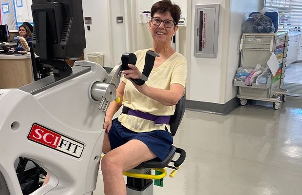 A person in a yellow shirt and blue skirt sitting on a exercise machine