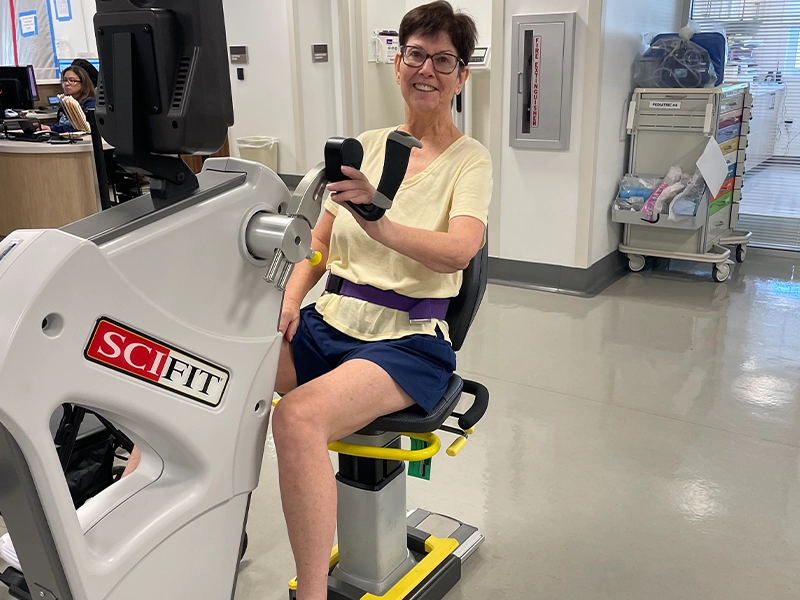 A person in a yellow shirt and blue skirt sitting on a exercise machine