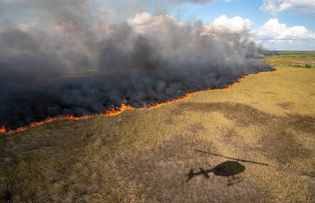 Shadow of a helicopter over a field of burning grass