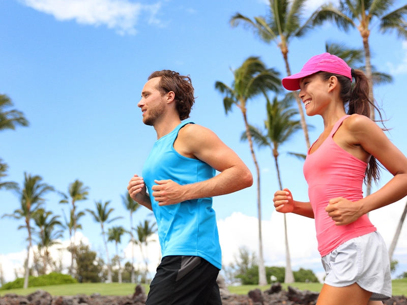 A man and a woman dressed in blue and pink are running in the park.