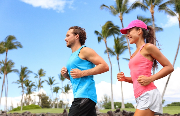 A man and a woman dressed in blue and pink are running in the park.