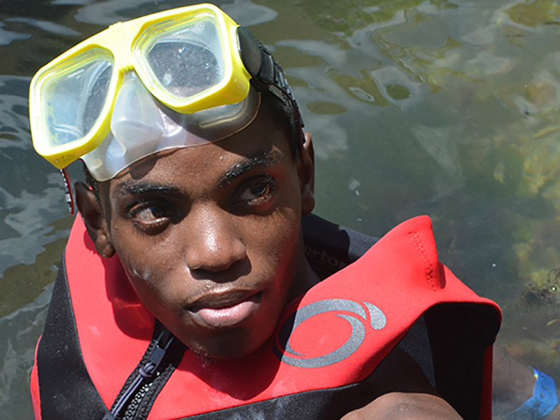 Aaron Willis wearing a life jacket and goggles, he's in the water