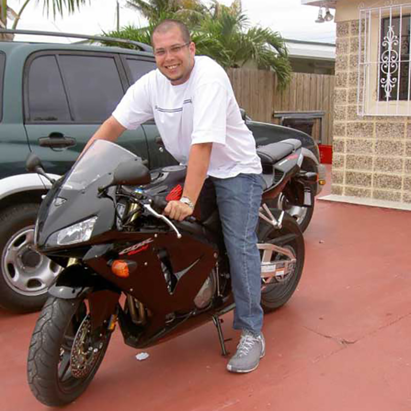 Erik on a motorcycle and smiling at the camera