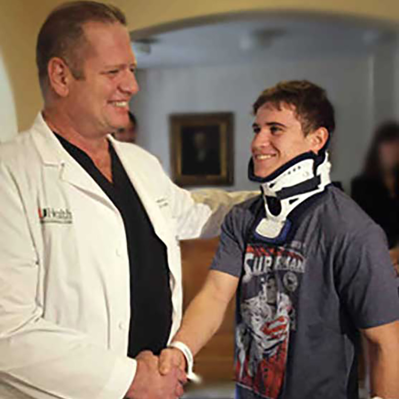 Jorge Valdes wearing a neck brace and shaking hands with a physician who is wearing a white coat