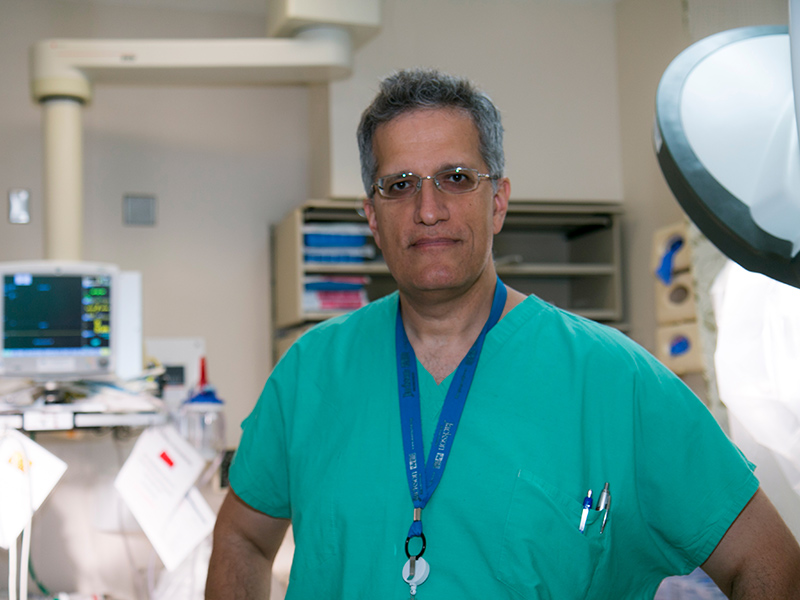 Nicholas standing inside a medical room, he is wearing glasses and green scrubs