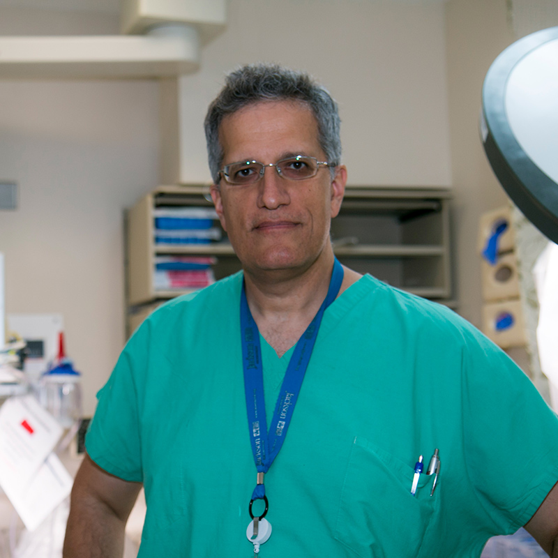 Nicholas standing inside a medical room, he is wearing glasses and green scrubs