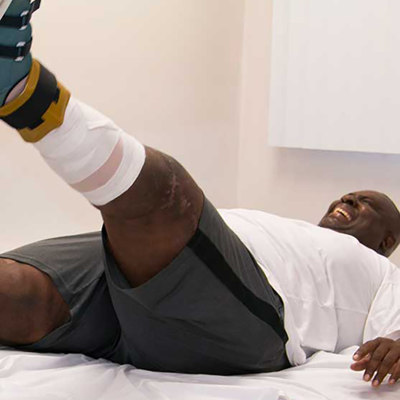 Robert Billue during a therapy session, he is laying down and lifting his left leg
