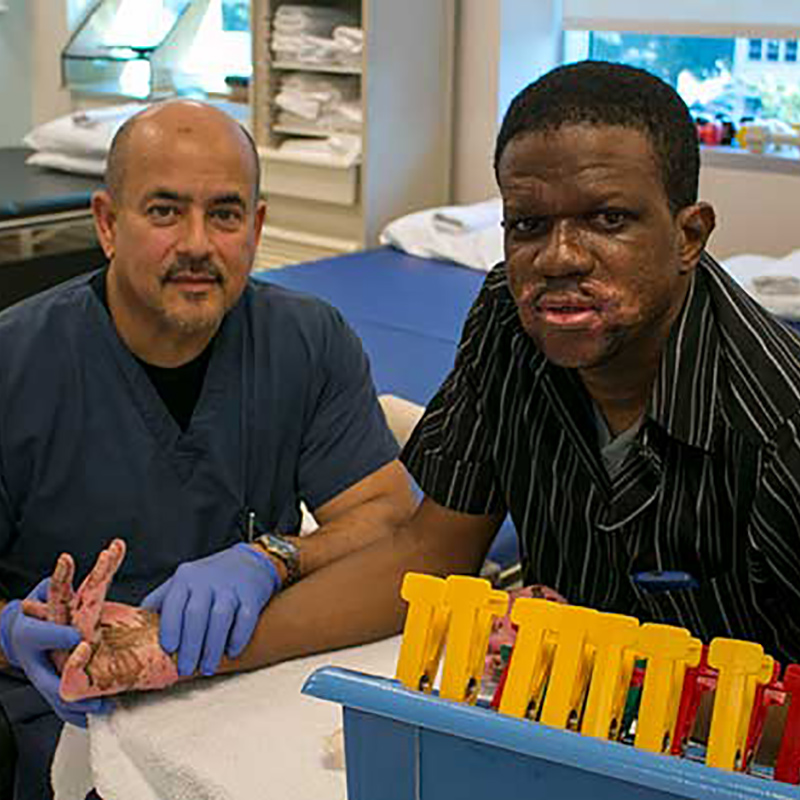 Tennyson McFarlane sitting with his therapist, they are both looking at the camera during a therapy session