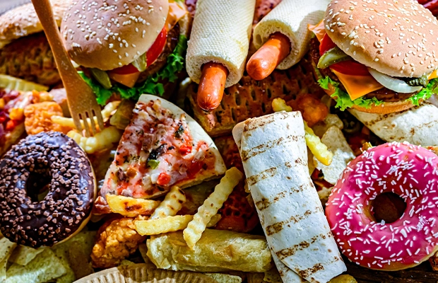 A photograph showing donuts, hot dogs, hamburgers, tildes, and all kinds of fast food.