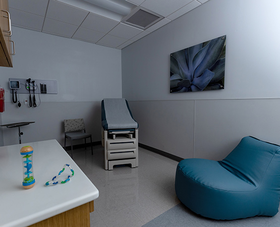 A dark medical room with a blue bean bag chair and sensory items on a table