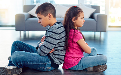 Children sitting on the floor lying back to back