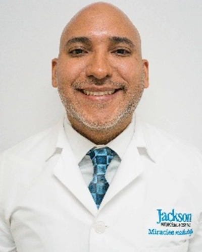 Professional headshot of Silva-Toro, a man smiling, against a white studio background