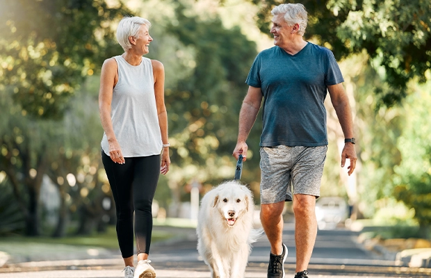 Senior couple walking in the park with their dog