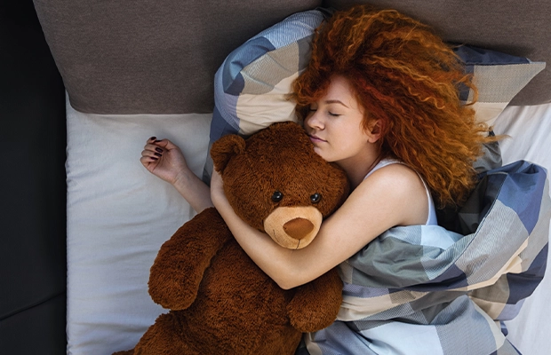 Women sleeping with a teddy bear