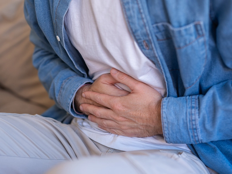 Close-up of a man's hands placed on his stomach as if he were in severe pain.