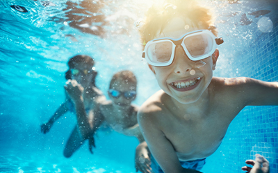 children smiling underwater in the pool