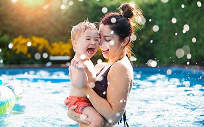 mom lifting her son in the pool