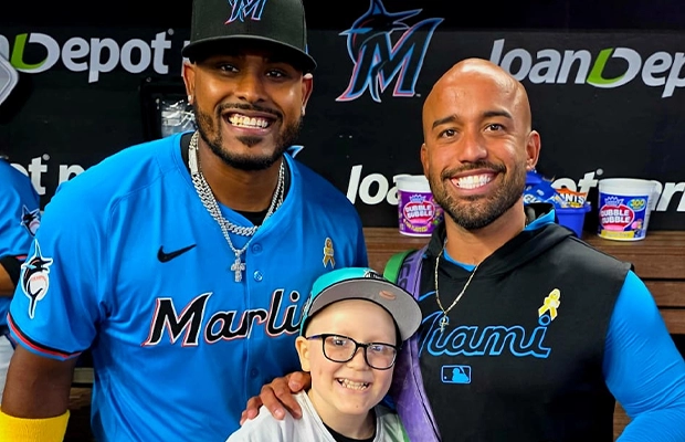 Two men posing next to a child with cancer.