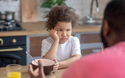 child making a bad face while they feed him