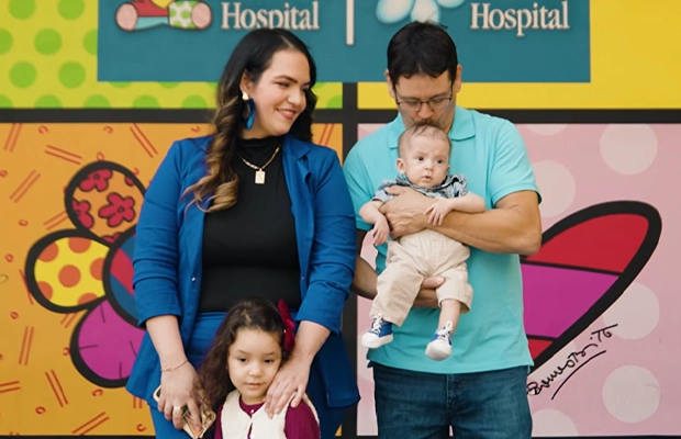 Photograph of a family with a colorful mural behind them.