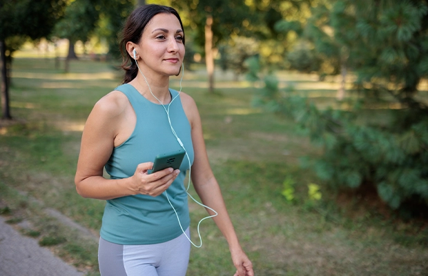 Woman in sportswear and short hair walking in the park while listening to something on her headphones