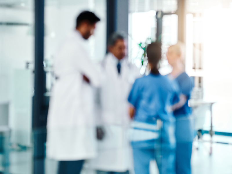 Blurry image of four medical practitioners speaking in a hospital