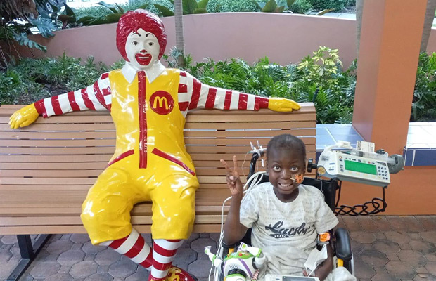 Child with oxygen mask smiling next to McDonald's clown