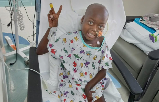 Boy lying on hospital stretcher making peace and love sign