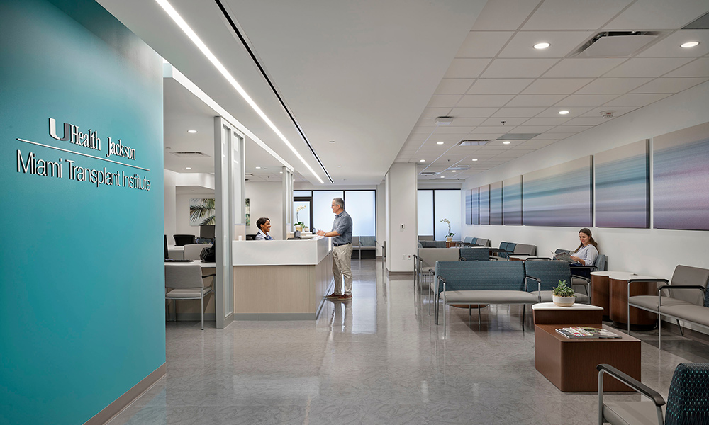 Miami Transplant Institute lobby, there is a person being checked in by a receptionist and one person waiting