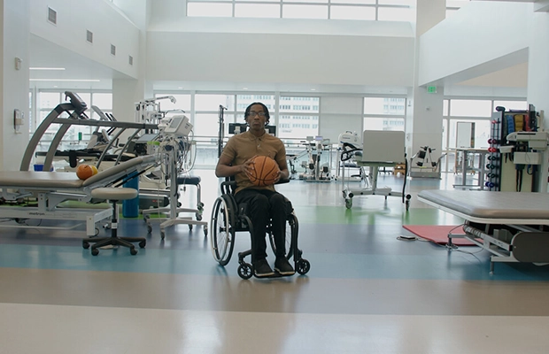 Young person in a wheelchair with a basketball in their hands.