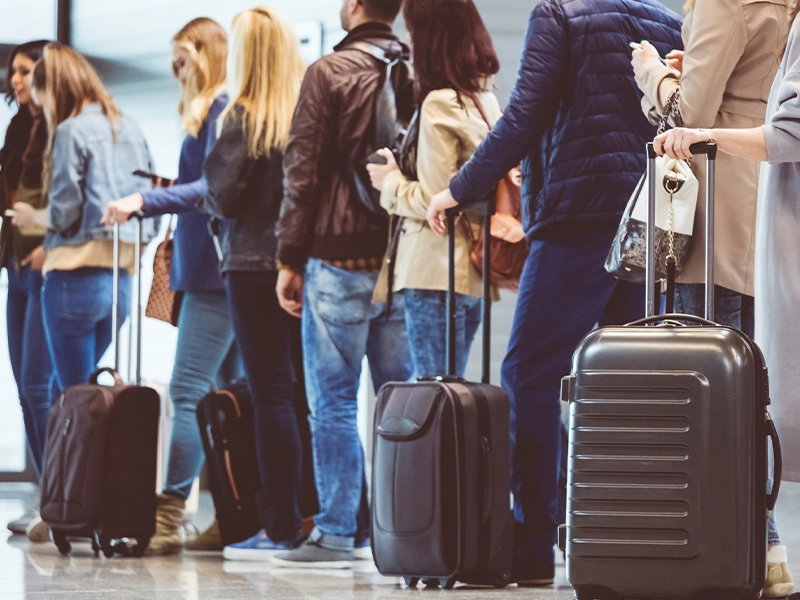 Photograph of several people queuing at the airport.