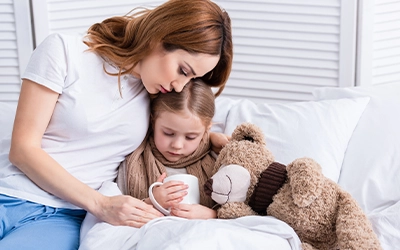 Woman hugging her little daughter who is holding a teddy bear