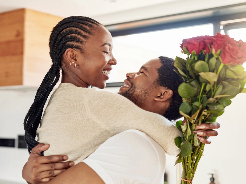 Couple kissing with a bouquet of flowers in their hands
