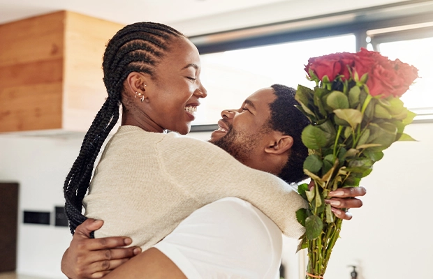 Couple kissing with a bouquet of flowers in their hands