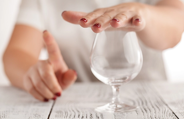 Close-up of a hand covering a glass of champagne