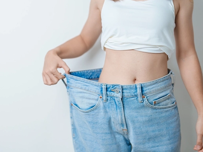 Woman showing that her jeans are too big because she lost weight