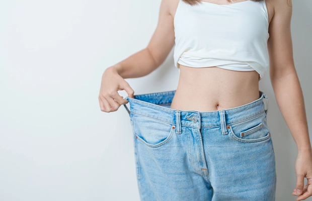 Woman showing that her jeans are too big because she lost weight