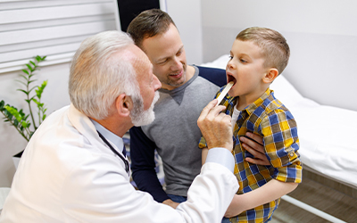 boy being checked by a doctor with his father
