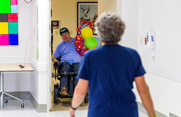 James “Woody” Beckham smiling as he comes through the door with birthday balloons