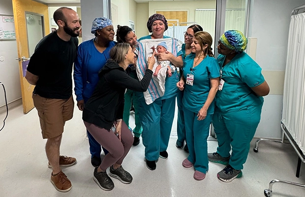 group of doctors and nurses holding a small baby