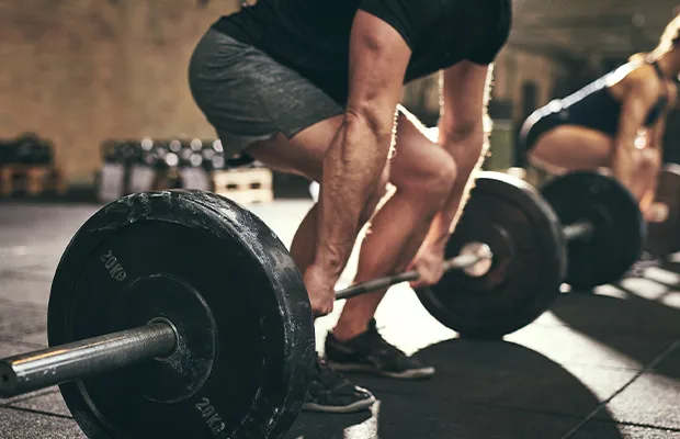 man in gray shorts and black t-shirt lifting weights in the gym