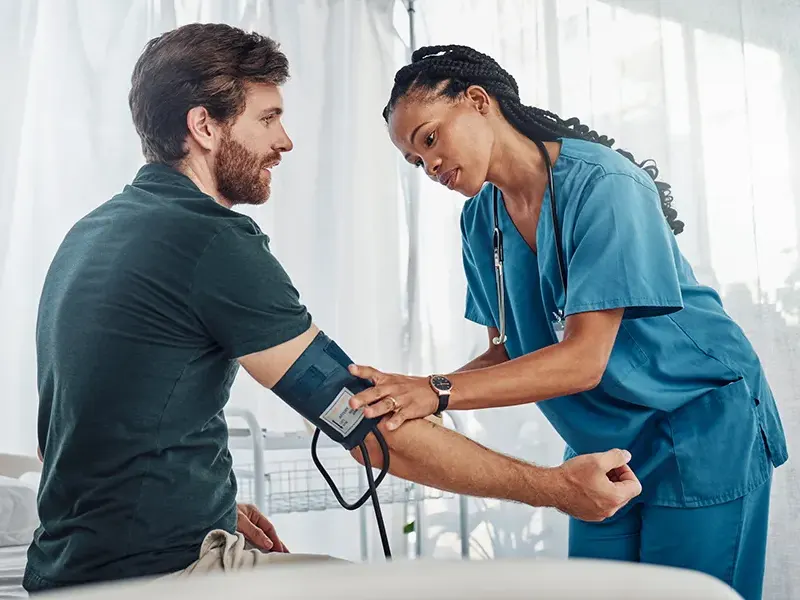 A medical professional putting a blood pressure cuff on a male patient