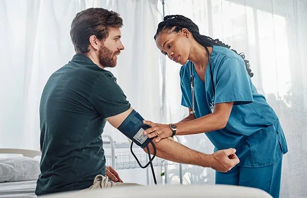A medical professional putting a blood pressure cuff on a male patient
