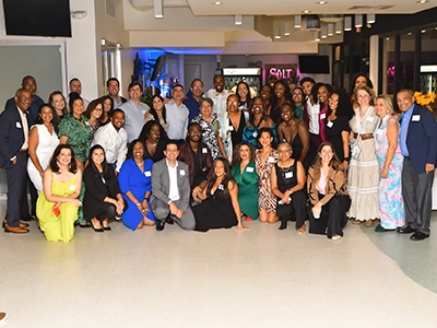 large group of people dressed in evening clothes smiling and posing for the camera