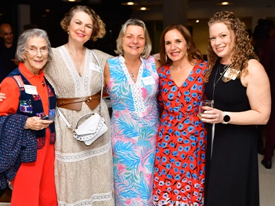 five women in long dresses smiling at the camera