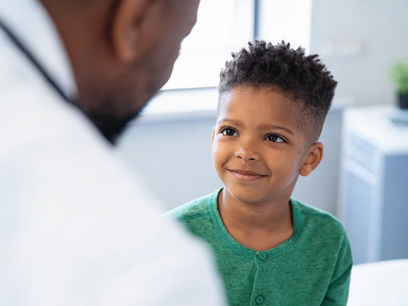 A young child smiling at a medical professional