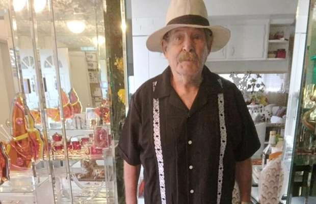 Old man with a hat is posing while smiling to the camera